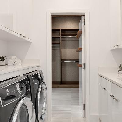 Utility room with white cabinets looking through to empty pantry