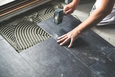 Slate effect tiles being laid on floor